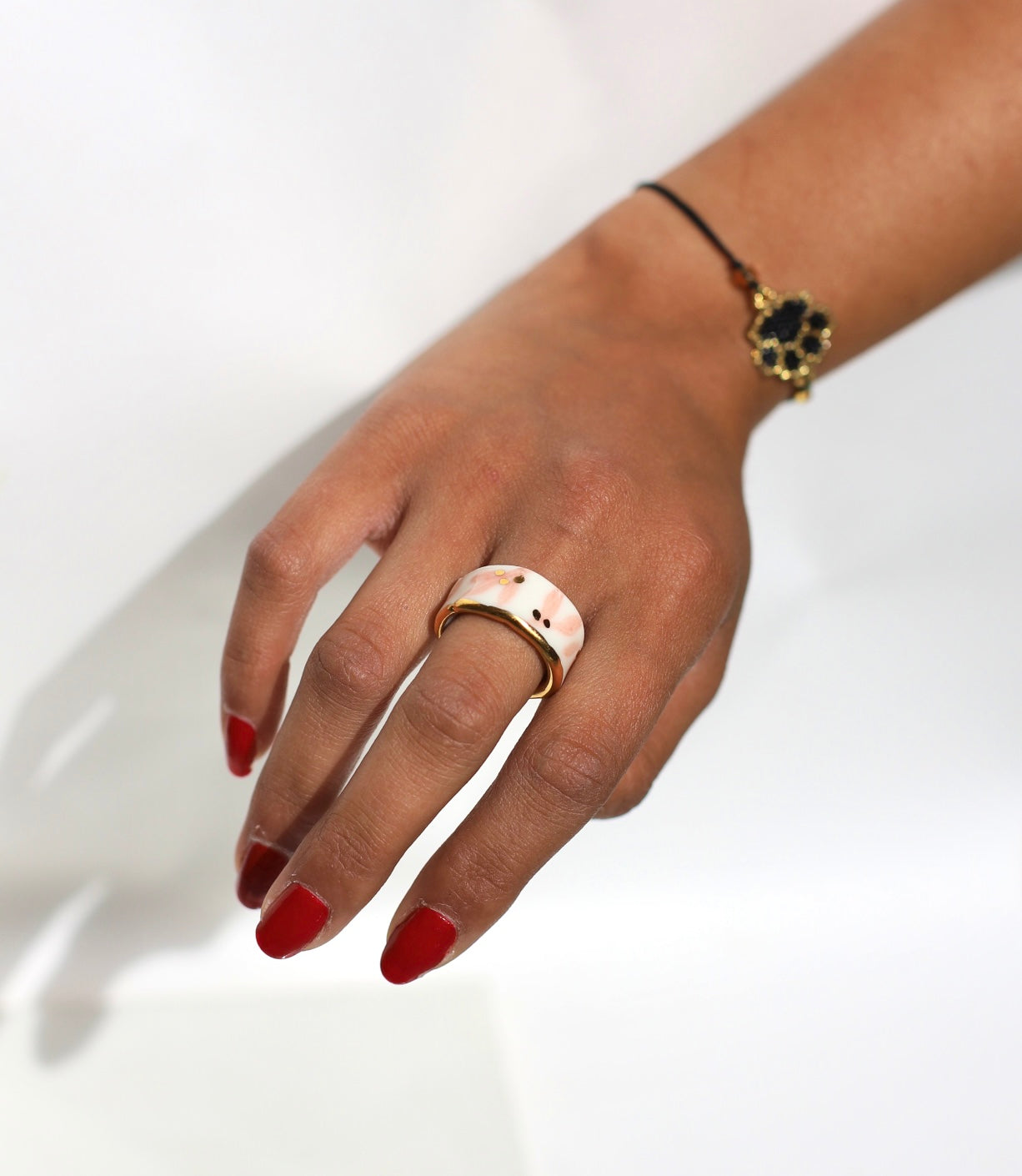 bague large en porcelaine blanche émaillée en taille 53 Fr, à motif fleurs rose et de points à l'or liquide fait à la main avec un liseré doré sur sa tranche.