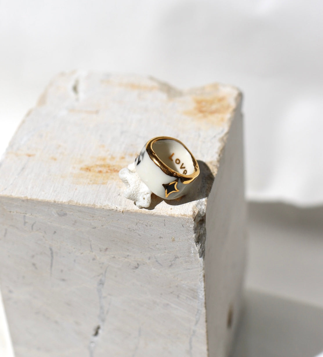 Bague large type bandeau en porcelaine blanche émaillée en taille 53 FR avec un message FUCK ornées de petits motifs d'étoiles en or liquide peintes à la main.
