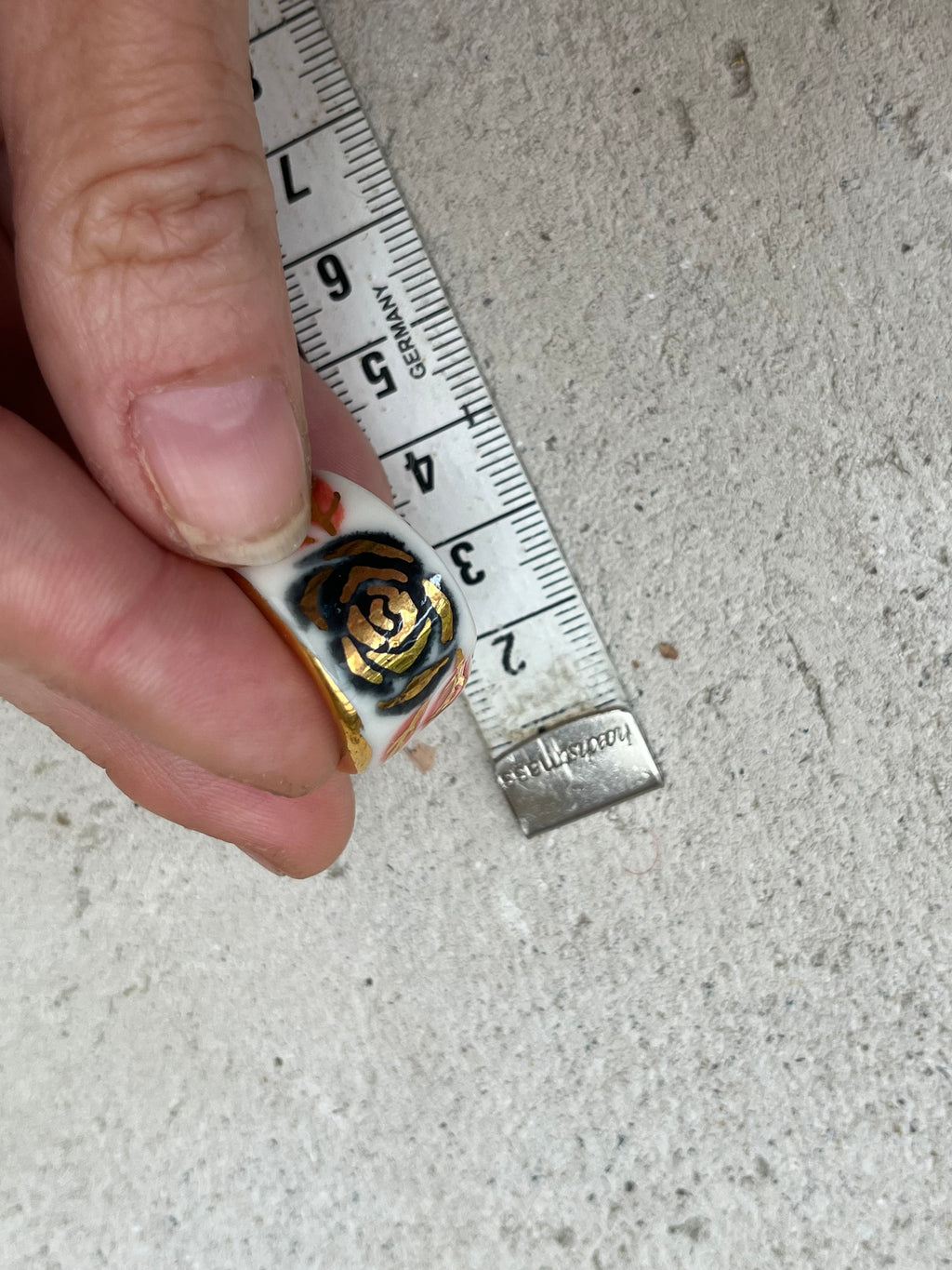 Une bague en porcelaine blanche émaillée en taille 51. Avec un motif rose noire stylisée peinte à l'or liquide avec des feuilles colorées. Avec une inscription  cachée "LOVE" en lettres dorées. Réalisée à la main à Lyon. 