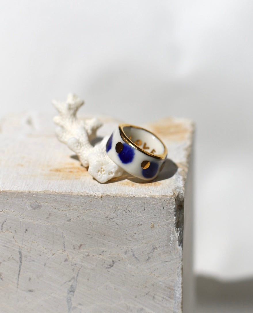 bague en porcelaine blanche émaillée en taille FR51, avec des détails à l'or liquide peint à la main avec un motif à pois bleu nuit et point à l'or précieux.