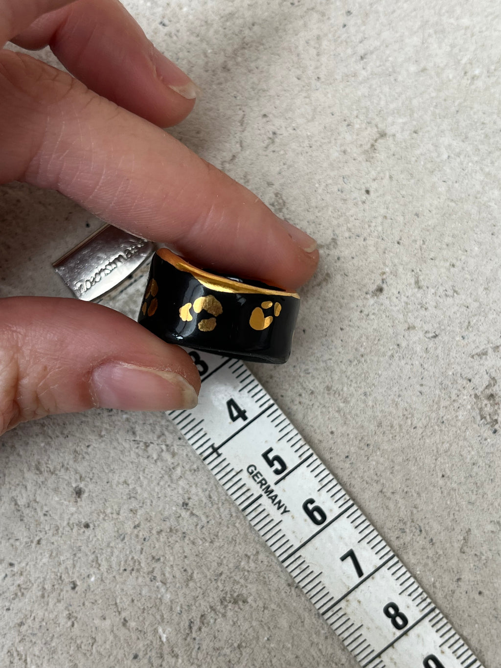 Une bague en porcelaine noir émaillée en taille 49, à motif léopards avec des tâches d'or liquide
