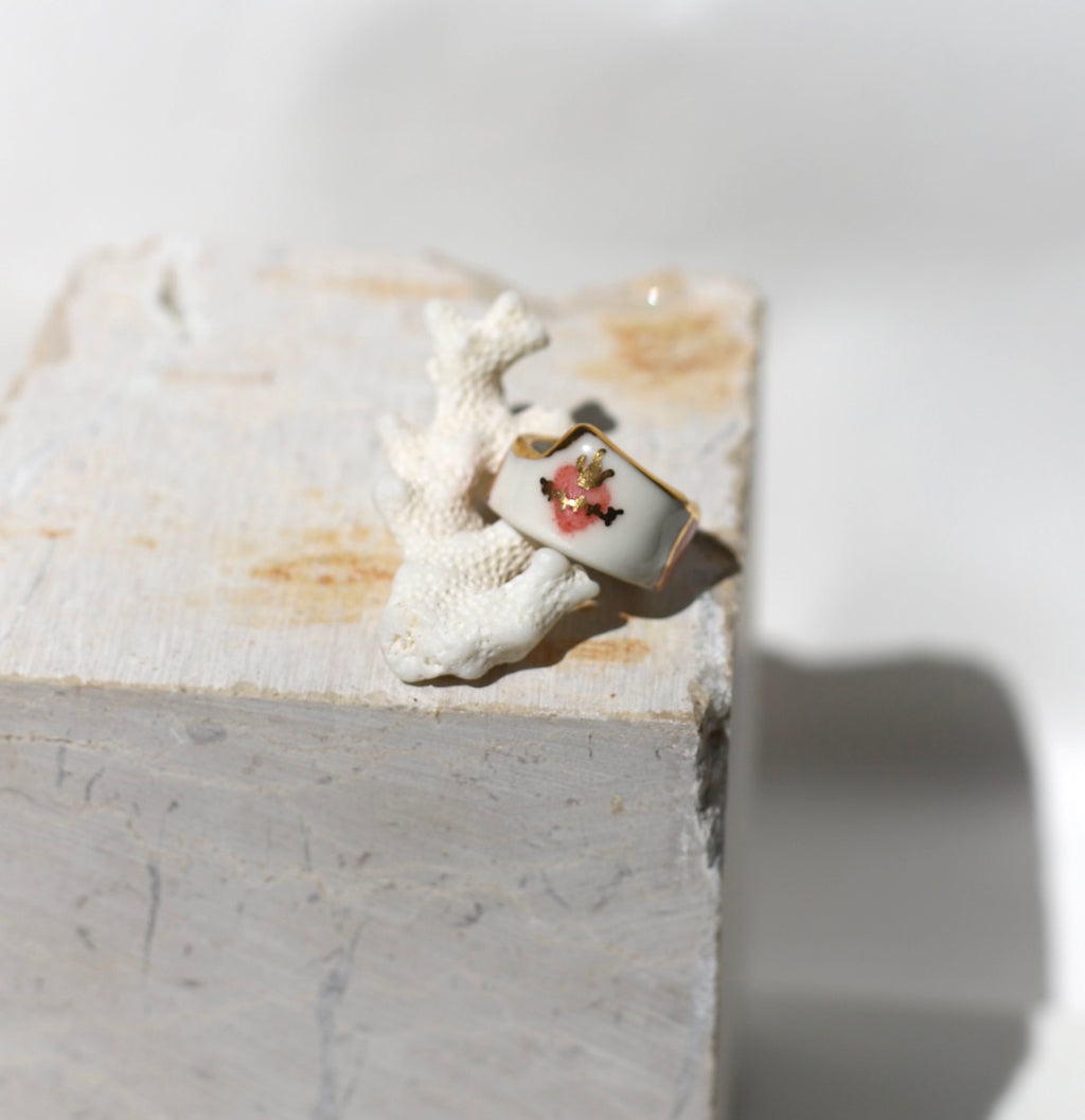 Bague large en porcelaine blanche émaillée en taille 52FR.  motif cœur ex-voto peinte à la main avec des détails en noirs et or. Fait à la main 