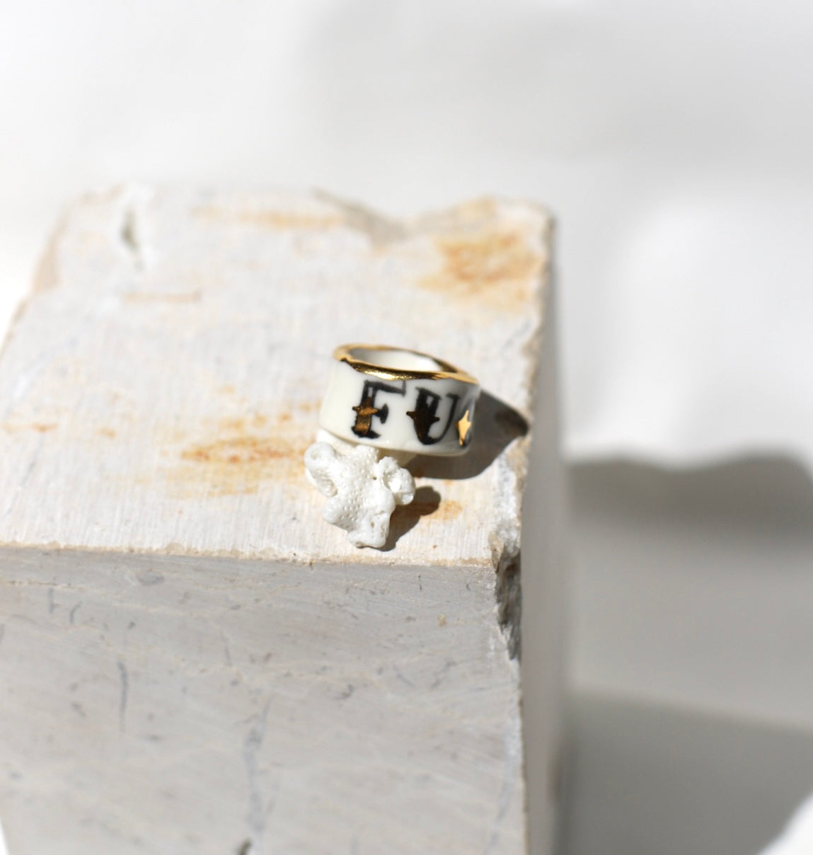 Bague large type bandeau en porcelaine blanche émaillée en taille 53 FR avec un message FUCK ornées de petits motifs d'étoiles en or liquide peintes à la main.