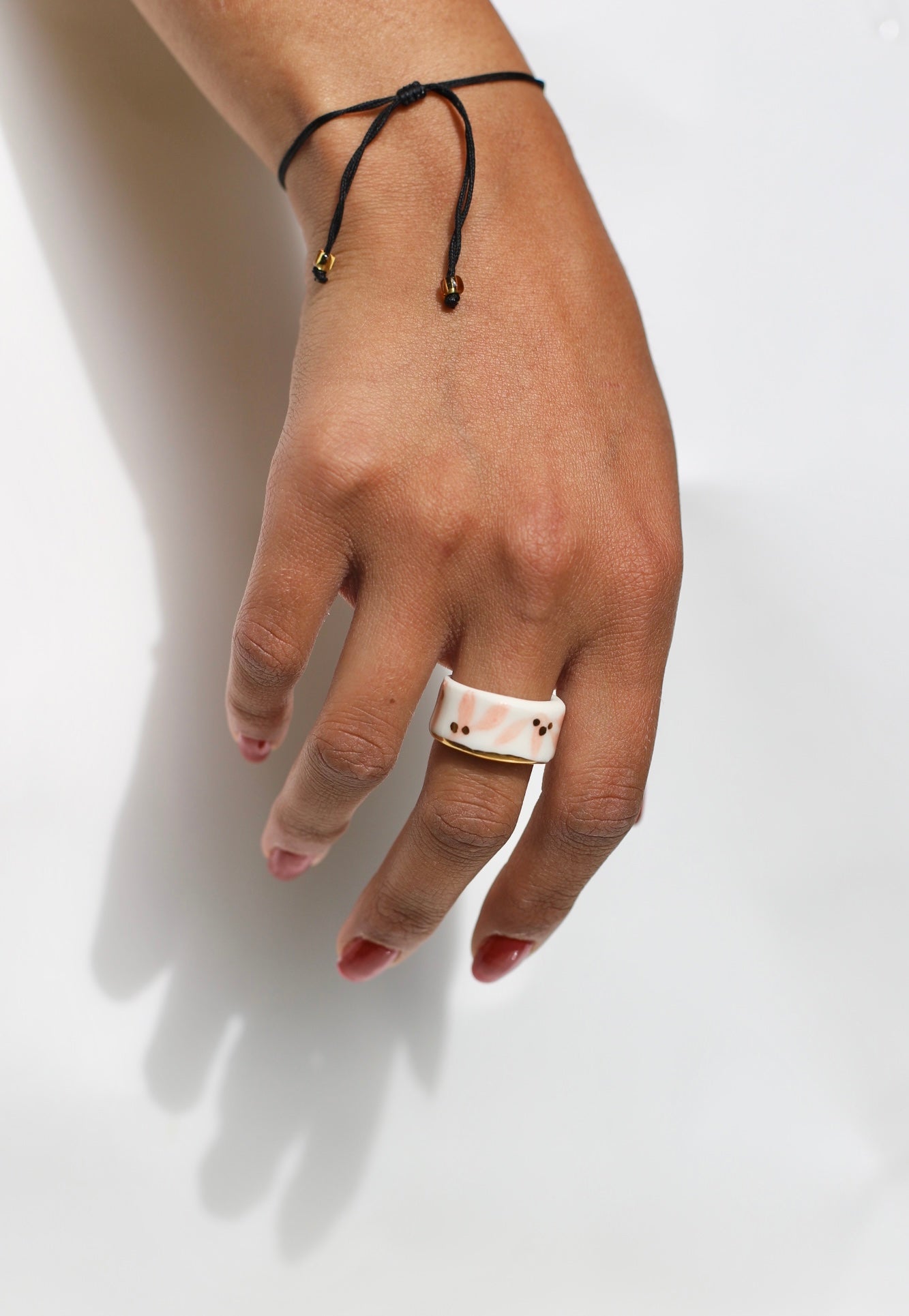 bague anneau large en porcelaine blanche émaillée en taille 53 Fr, à motif fleurs rose et de points à l'or liquide fait à la main avec un liseré doré sur sa tranche.
