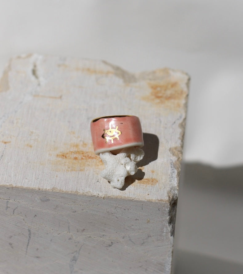 bague en porcelaine rose émaillée taille 52 FR avec une inscription "amour" écrite ainsi qu'un œil protecteur dessiné à la main à l'or liquide.