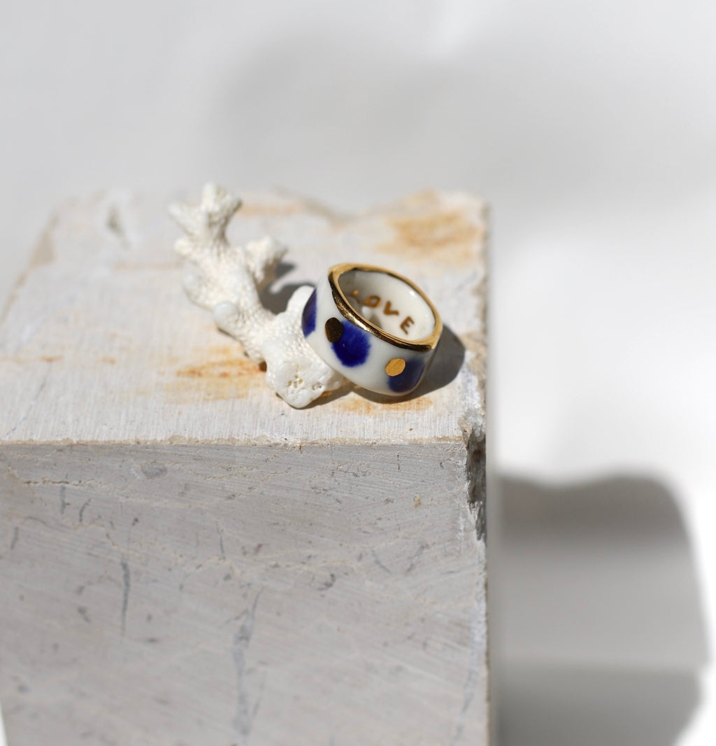 bague en porcelaine blanche émaillée en taille FR51, avec des détails à l'or liquide peint à la main avec un motif à pois bleu nuit et point à l'or précieux.