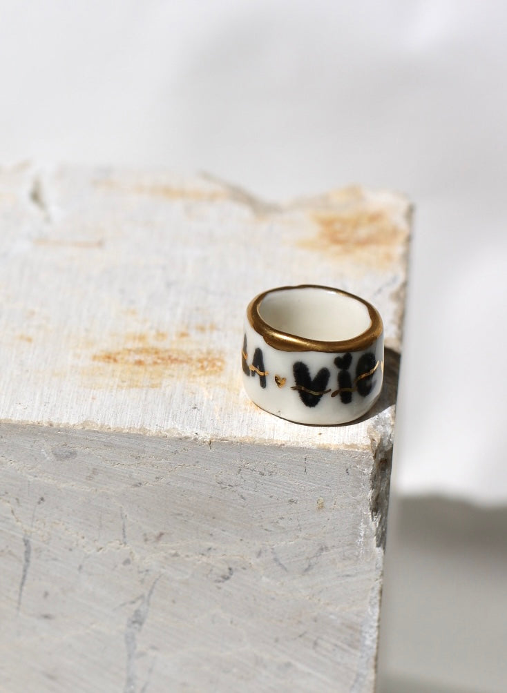 Bague en porcelaine blanche avec inscription noire la vie la pute et liseré or  taille 52 FR.