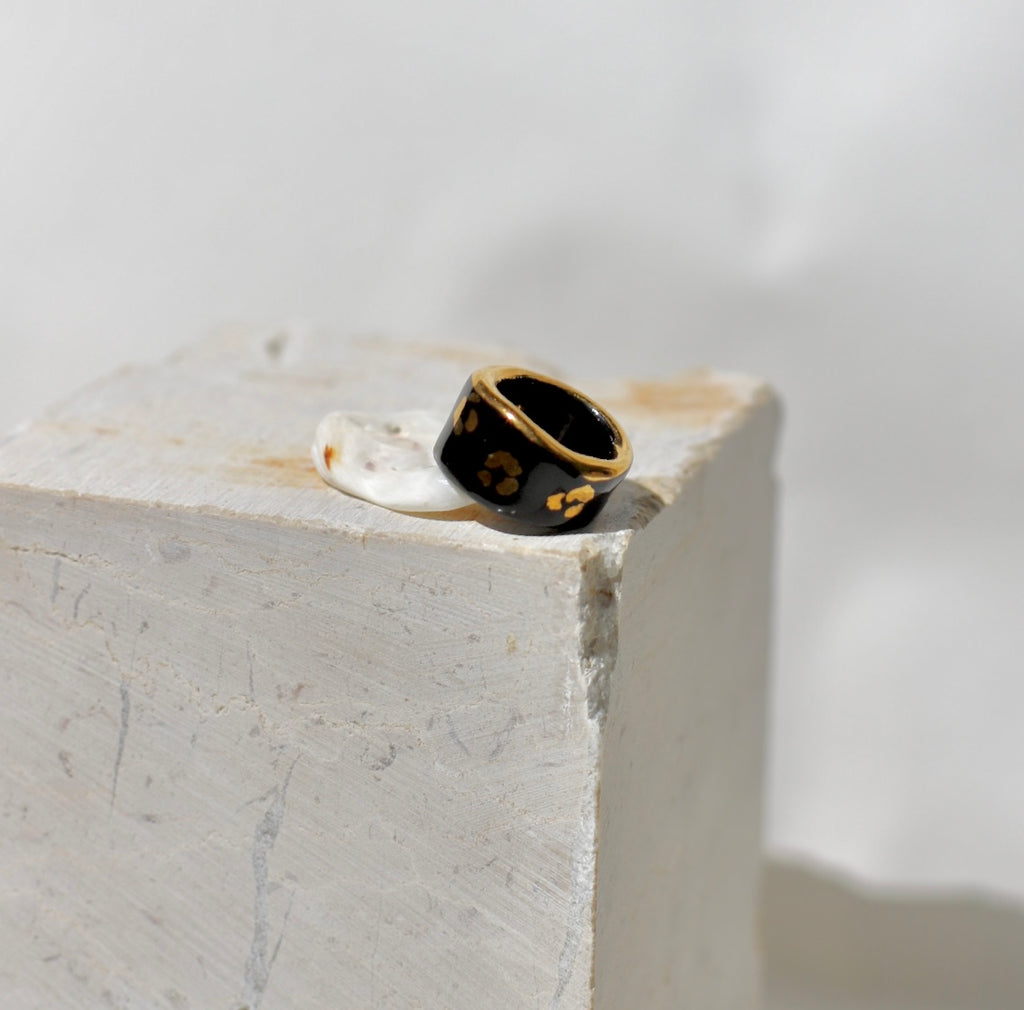 Une bague en porcelaine noir émaillée en taille 49, à motif léopards avec des tâches d'or liquide
