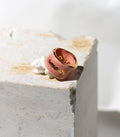 bague de type bandeau en porcelaine rose émaillée en taille 52 FR avec une inscription "amour" écrite ainsi qu'un œil protecteur dessiné à la main à l'or liquide.
