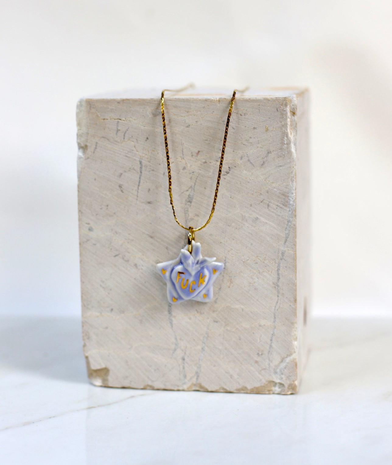 Collier en porcelaine en forme d'étoile avec un coeur ex-voto peint à la main avec une sériation fuck peint à l'or liquide 