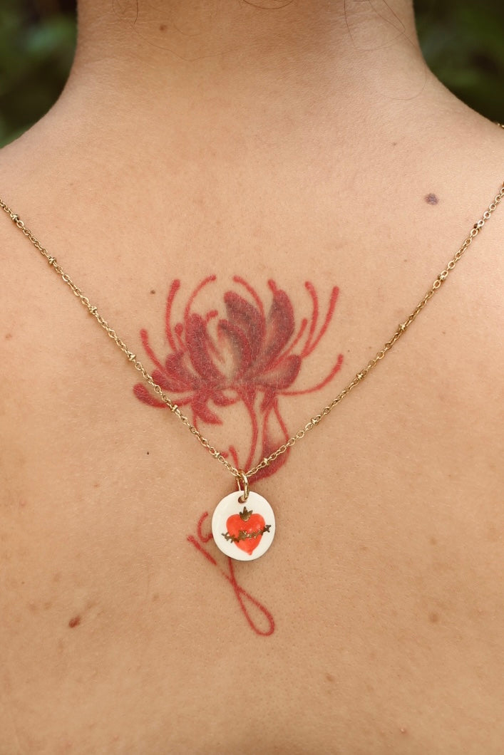 Pendentif en porcelaine avec un sacré coeur rouge peint à la main avec des détails à l'or liquide 
