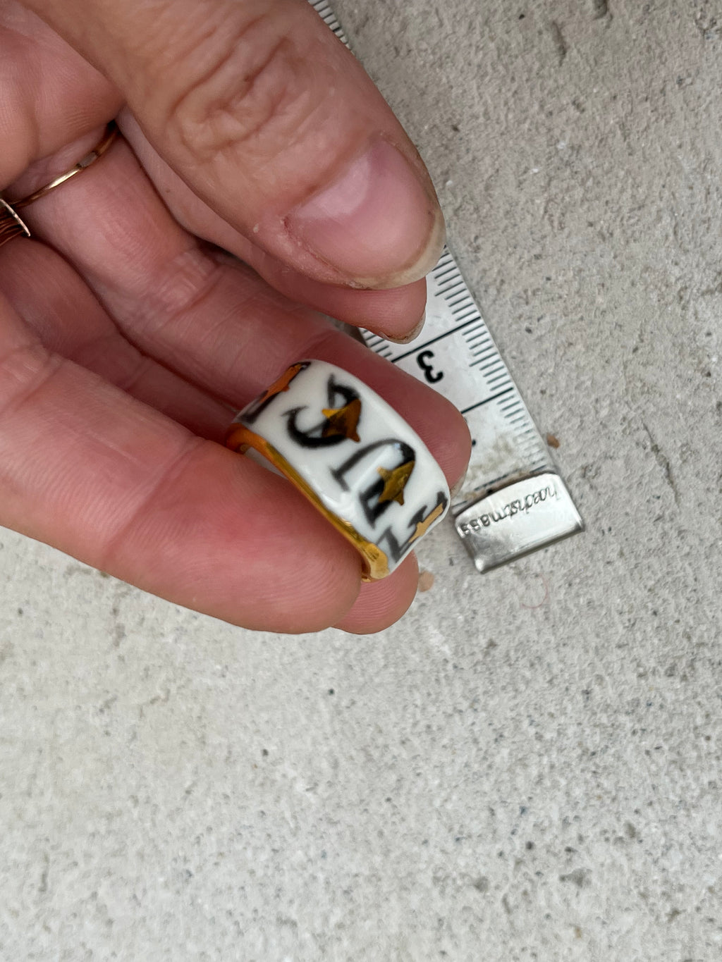 Bague en porcelaine blanche émaillée en taille 53 FR avec un message FUCK ornées de petits motifs d'étoiles en or liquide peintes à la main.