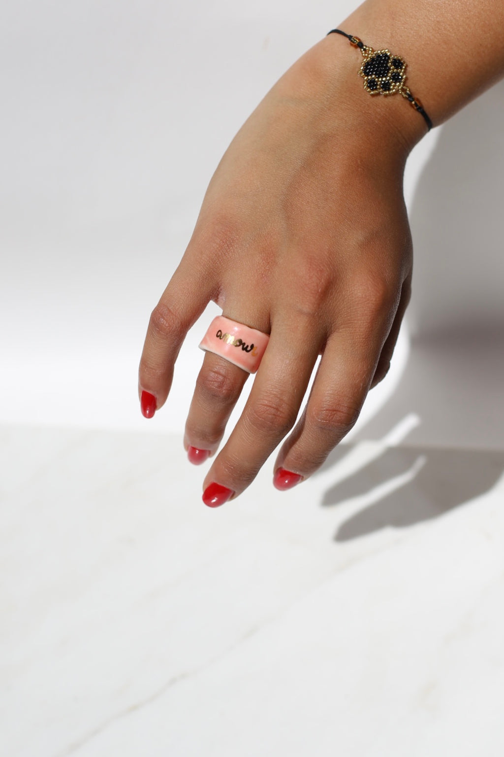 bague en porcelaine rose émaillée taille 52 FR avec une inscription "amour" écrite ainsi qu'un œil protecteur dessiné à la main à l'or liquide.