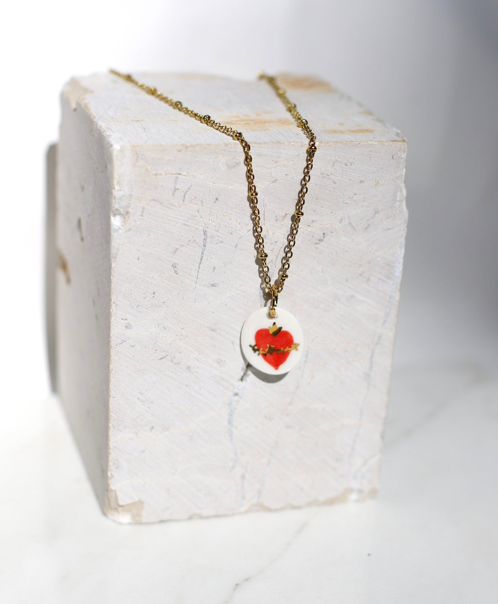 Pendentif en porcelaine émaillée avec un motif coeur  en rouge avec des détails peint à l'or liquide à la main 
