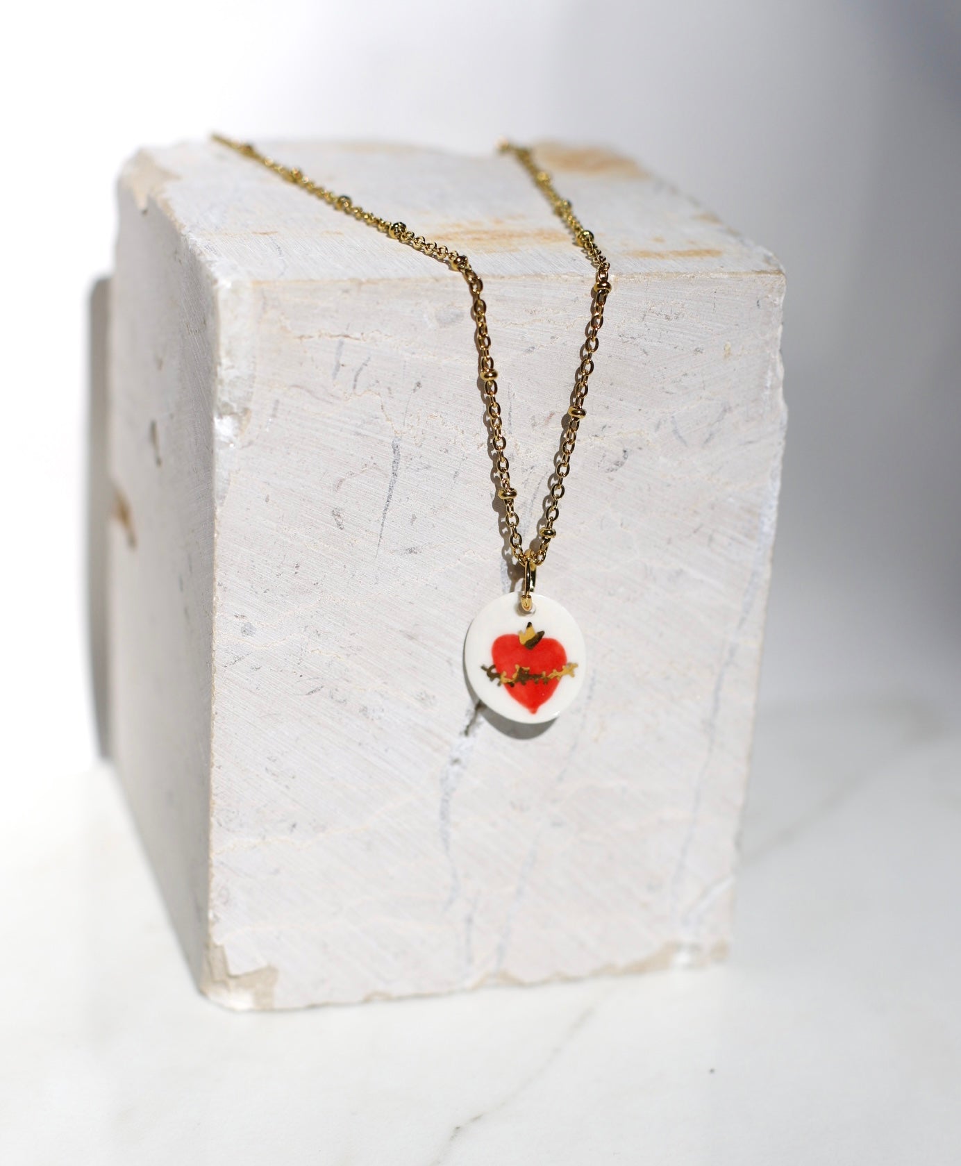 Pendentif en porcelaine émaillée avec un motif coeur  en rouge avec des détails peint à l'or liquide à la main 