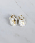 paire de boucles d'oreilles en porcelaine blanche, l'un portant l'inscription dorée LOVE et l'autre l'inscription dorée FUCK. Faites et peint à la main. 