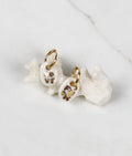 Paire de petites boucles d'oreilles pendantes asymétriques pour femme en porcelaine blanche, ornées des mots LOVE et FUCK écrits à l'or fin.