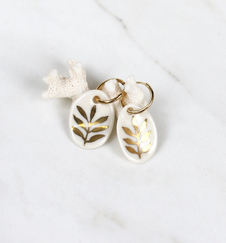 Boucles d'oreilles pendantes en porcelaine blanche avec motif feuillage en or fin. Bijou de créateur pour femme