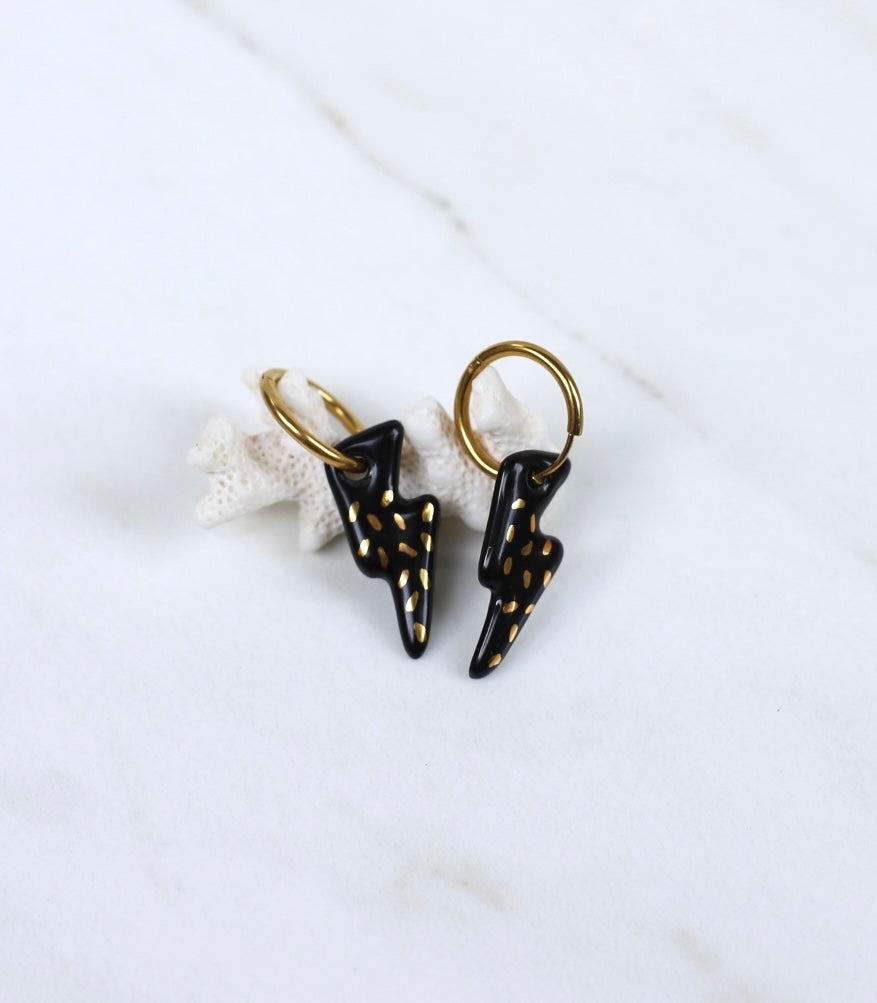  Paire de boucles d'oreilles dorées avec des pendentifs en forme d'éclair noir ornés de petites touches dorées à l'or fin.