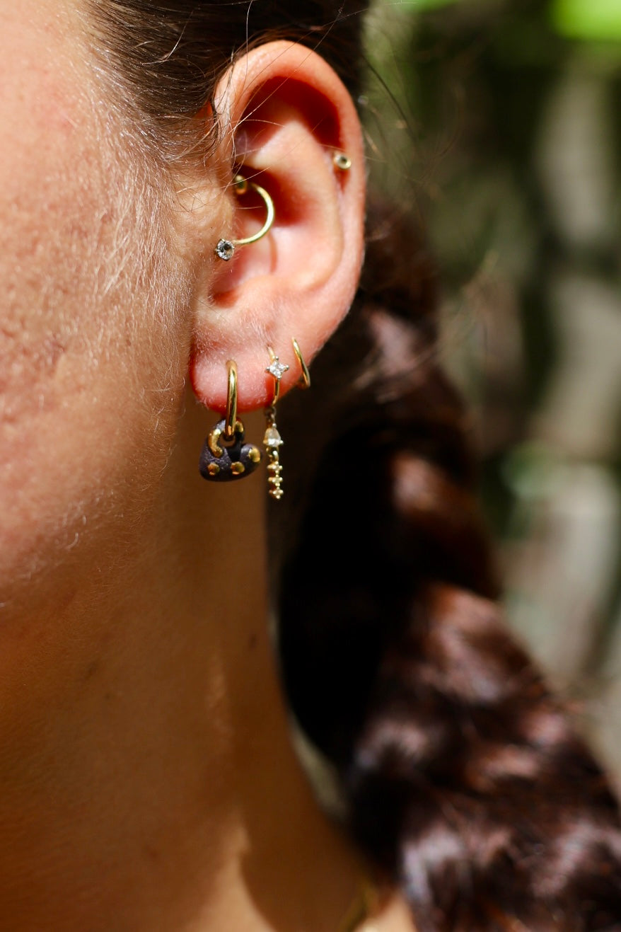 boucle d'oreille en porcelaine en forme de cœur noir, peint à la main et rempli de taches et de points dorés à l'or.