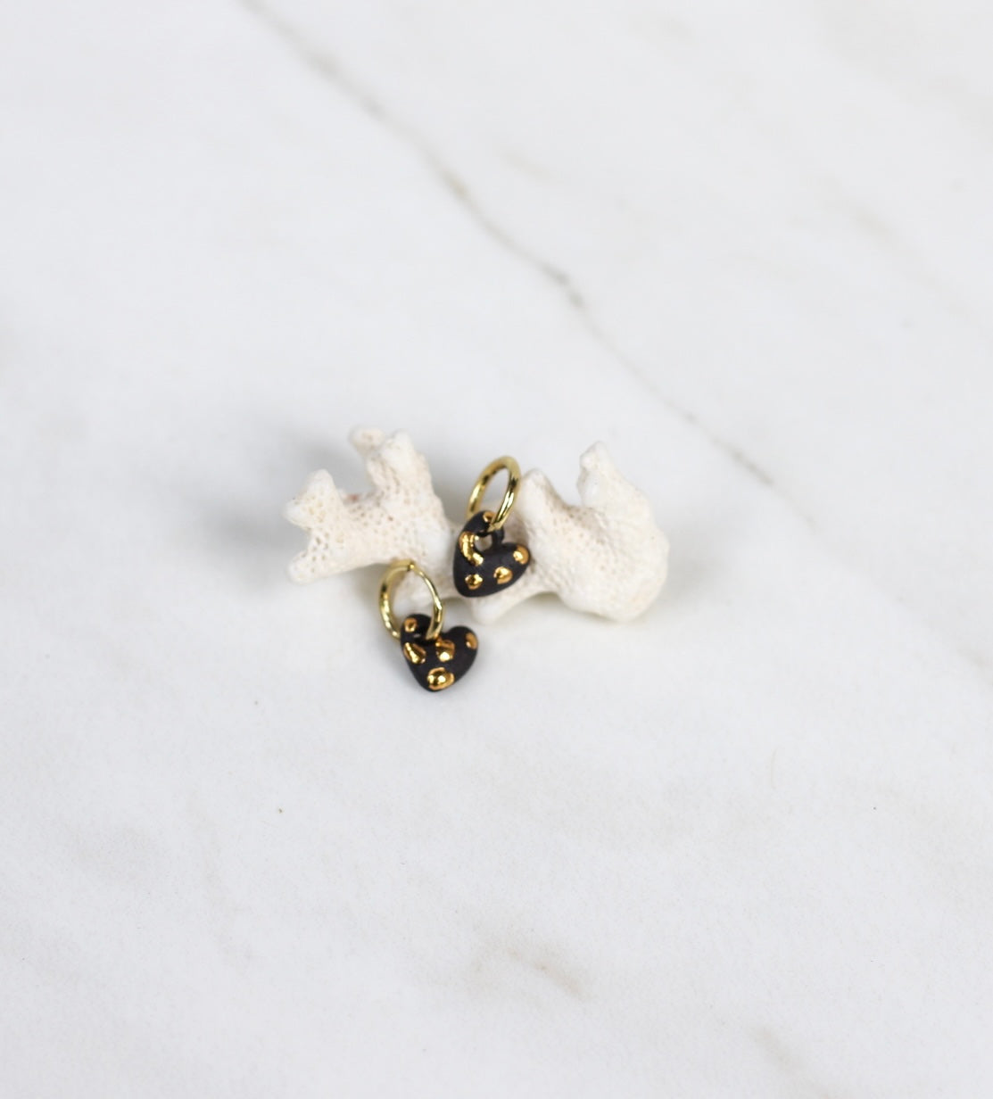 Mini paire de boucles d'oreilles en porcelaine noire matte pendantes en forme de petit cœur noir avec des détails à l'or fait main. 