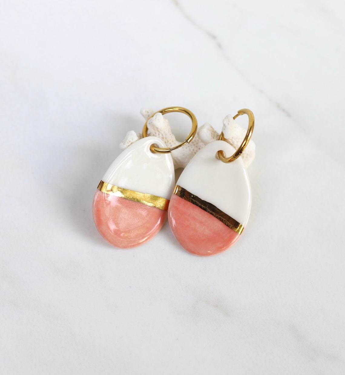 Paire de boucles d'oreilles  dorées avec de grands pendants en porcelaine émaillée blanche et rose saumon, séparés par un large bandeau d'or fin brillant