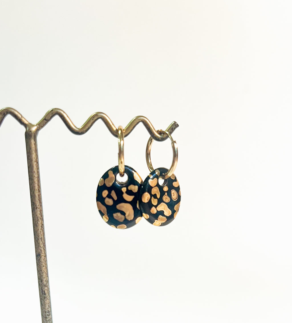 Une paire de boucles d'oreilles dorées avec des motif léopard en porcelaine noire  tacheté d'or fin fait à la main.