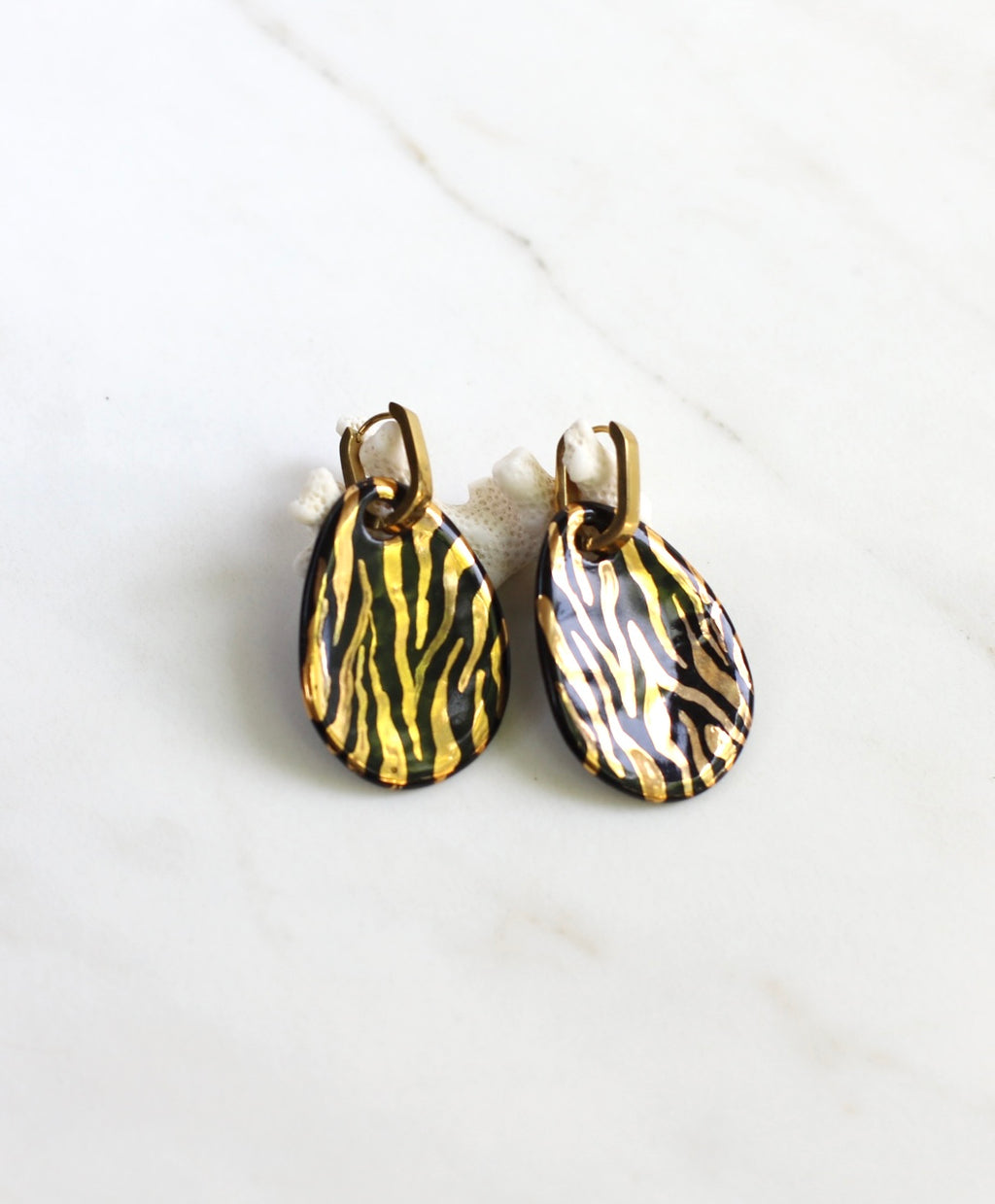 paire de boucles d'oreilles pendantes dorées dotées de pendentifs en porcelaine noire ornés d'un motif zébré à l'or fin