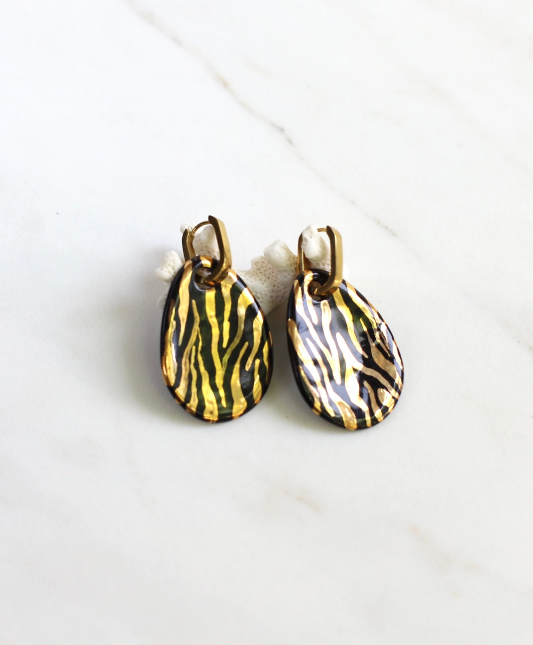 paire de boucles d'oreilles pendantes dorées dotées de pendentifs en porcelaine noire ornés d'un motif zébré à l'or fin
