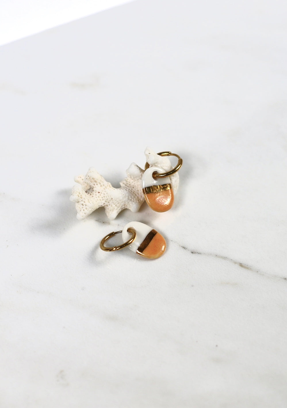 paire de boucles d'oreilles mini dorées avec en porcelaine bicolore blanche et couleur pêche, séparés par une ligne dorée