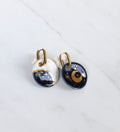 Une grande paire de boucles dépareillées en céramique, avec motif alchimie, lune et soleil bleu 