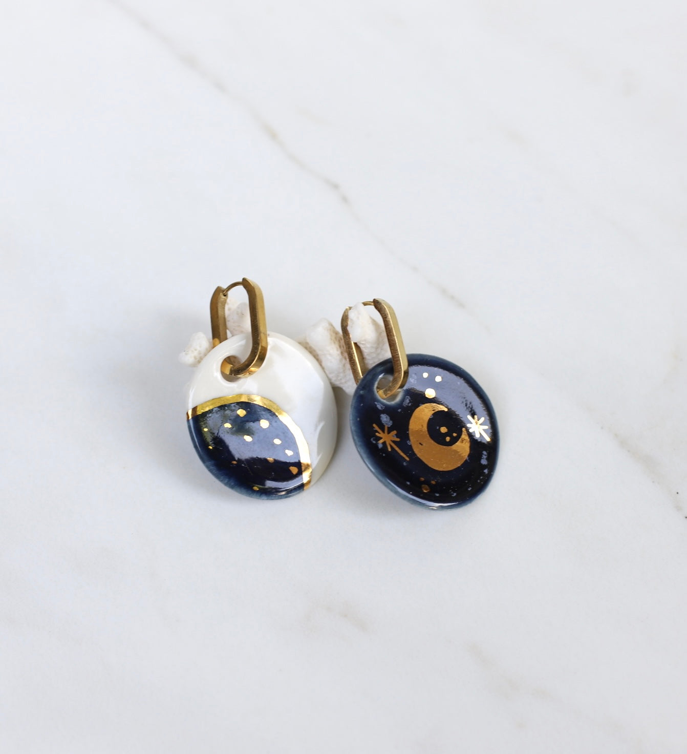 Une grande paire de boucles dépareillées en céramique, avec motif alchimie, lune et soleil bleu 