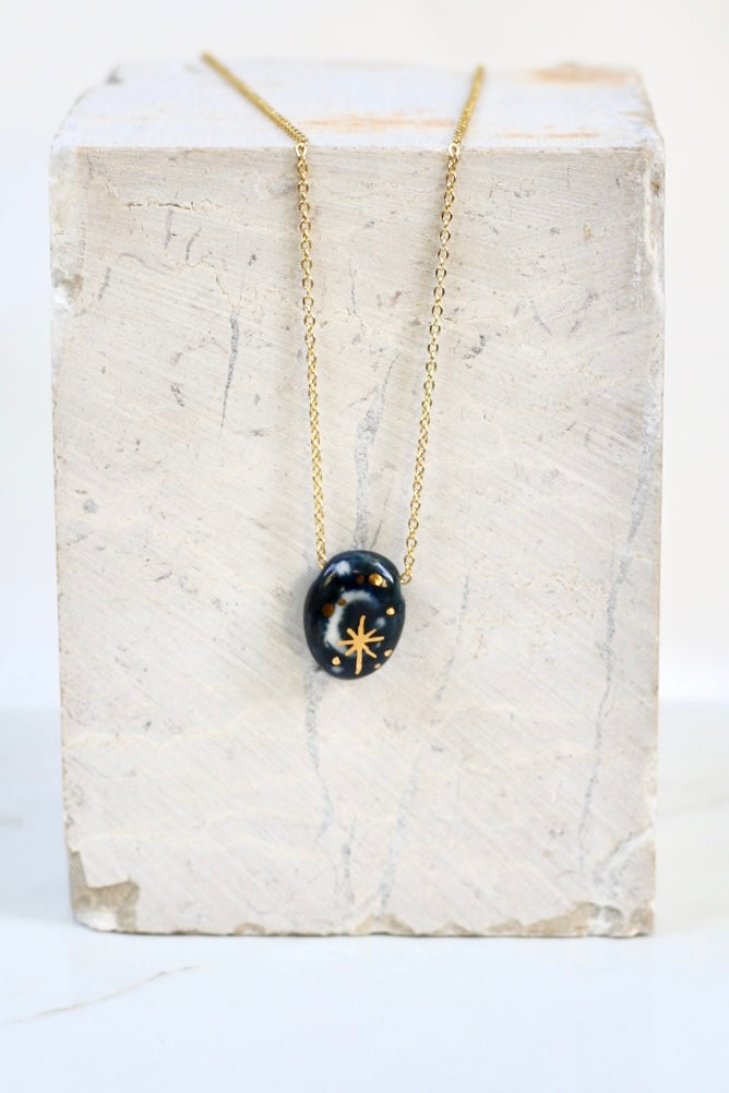 Collier céleste avec un pendentif ovale en porcelaine émaillée bleu foncé, avec un motif de croissant de lune et une grande étoile scintillante à l'or liquide peint à la main