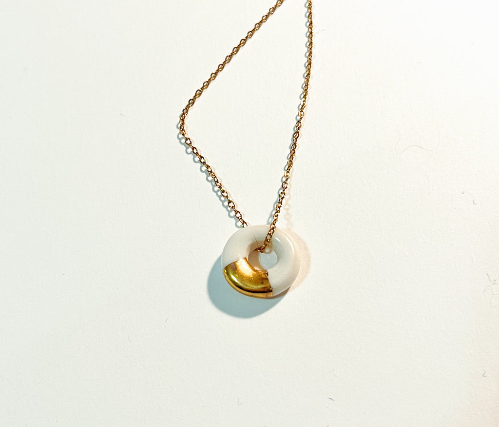 Collier de femme avec un pendentif en forme d'anneau avec une touche d'or et fait en porcelaine.