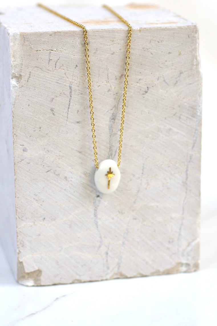 Collier délicat doté d'un petit pendentif ovale en porcelaine blanche émaillée avec son motif céleste d'étoile polaire à l'or liquide peint à la main