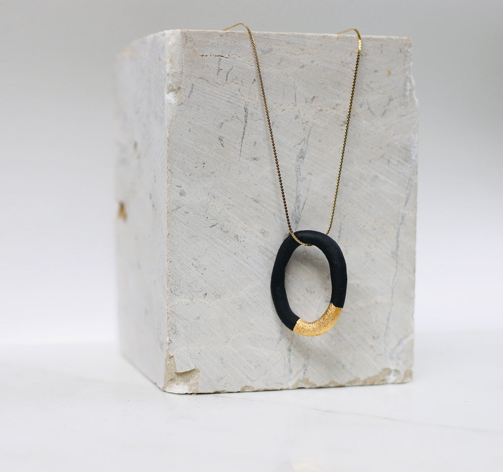 Collier créole avec une fine chaîne dorée et d'un pendentif anneau en porcelaine noire mate fait main.