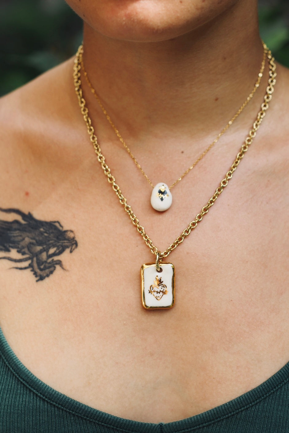 chaine en acier inoxydable avec un pendentif en porcelaine blanc fait main avec un motif de coeur enflammé noir avec des détails à l'or liquide. 