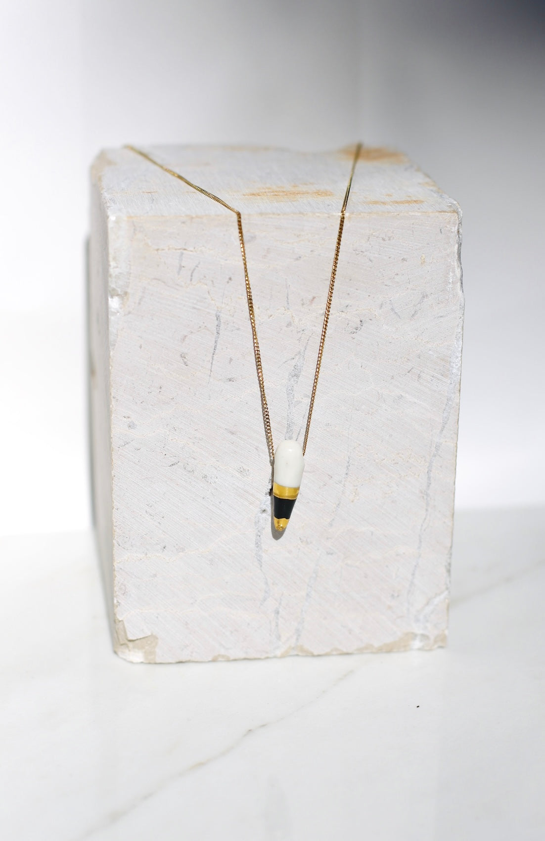 Collier avec un pendentif en forme de dent de requin en porcelaine fabriqué et peint à la main avec du noir et de l'or liquide 