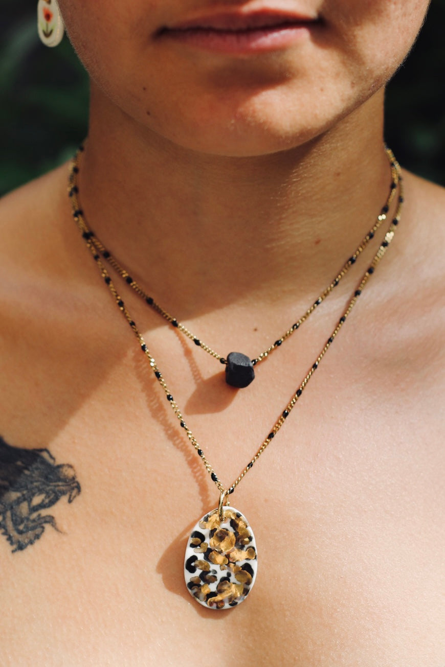 pendentif en porcelaine fait à la main à motif léopard tacheté de noir et d'or avec des détails peint  l'or liquide 