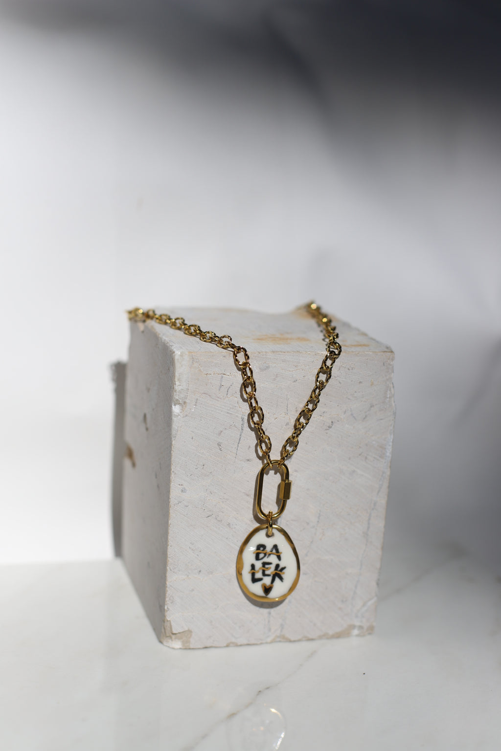 Collier en acier inoxydable avec des grosse chaîne et un médaillon en porcelaine fait à la main arborant le mot balek avec des détails à l'or peint à la main 