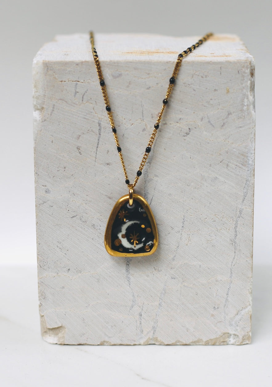 Collier avec un motif lune en porcelaine avec des touches d'or fait main