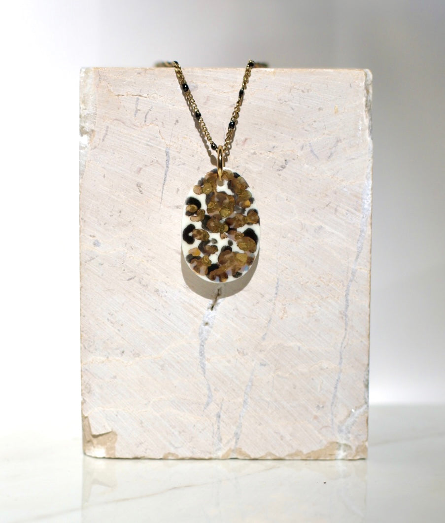 Collier tendance orné d'un pendentif ovale en porcelaine blanche émaillée, à motif léopard tacheté aux nuances de noir avec des détails peint à l'or liquide 