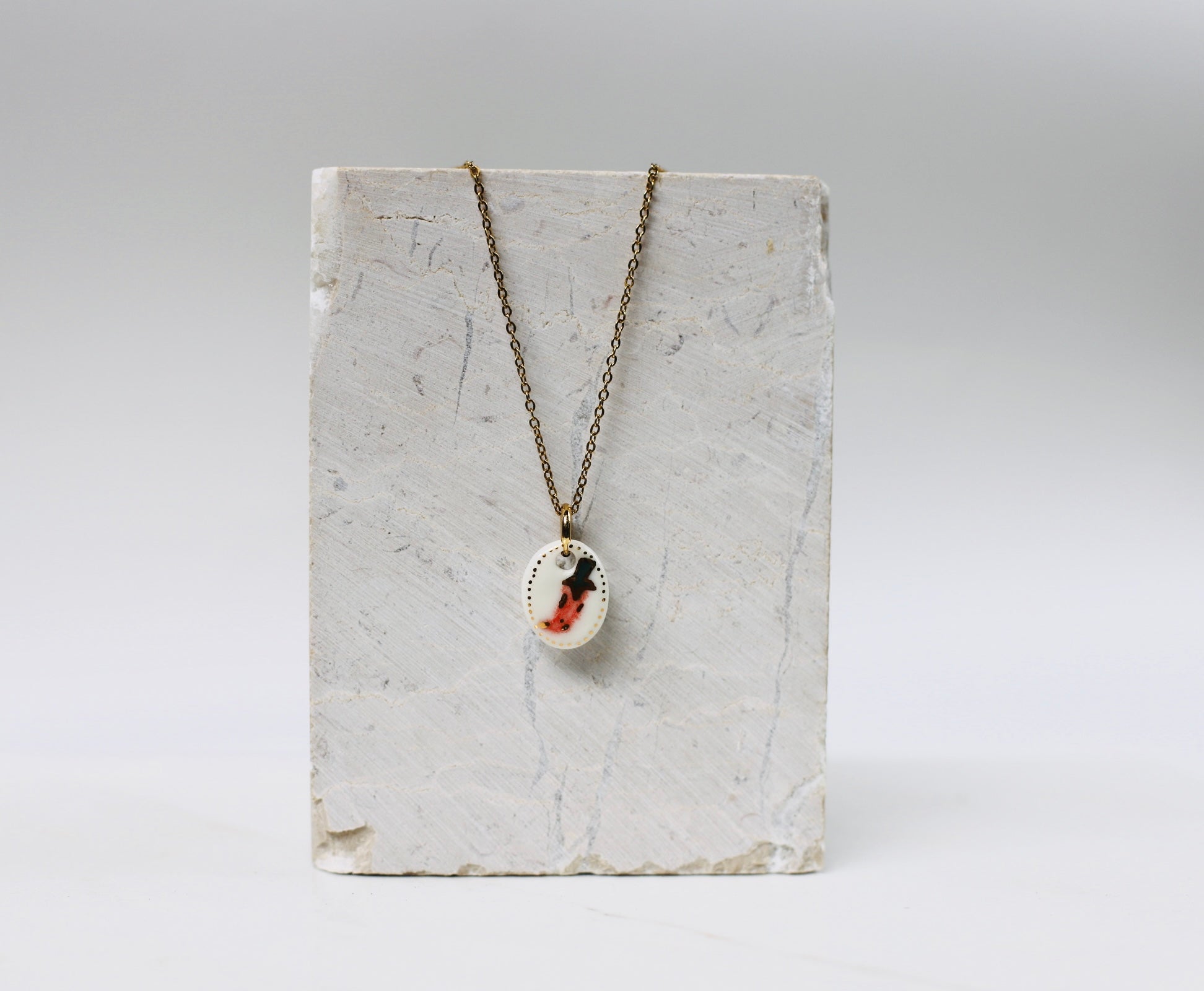 collier avec son médaillon en porcelaine blanche peint à la main d'un motif piment rouge.