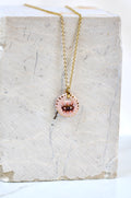 collier talisman orné d'un pendentif en porcelaine rose à motif œil de protection peint à la main avec des détails à l'or liquide