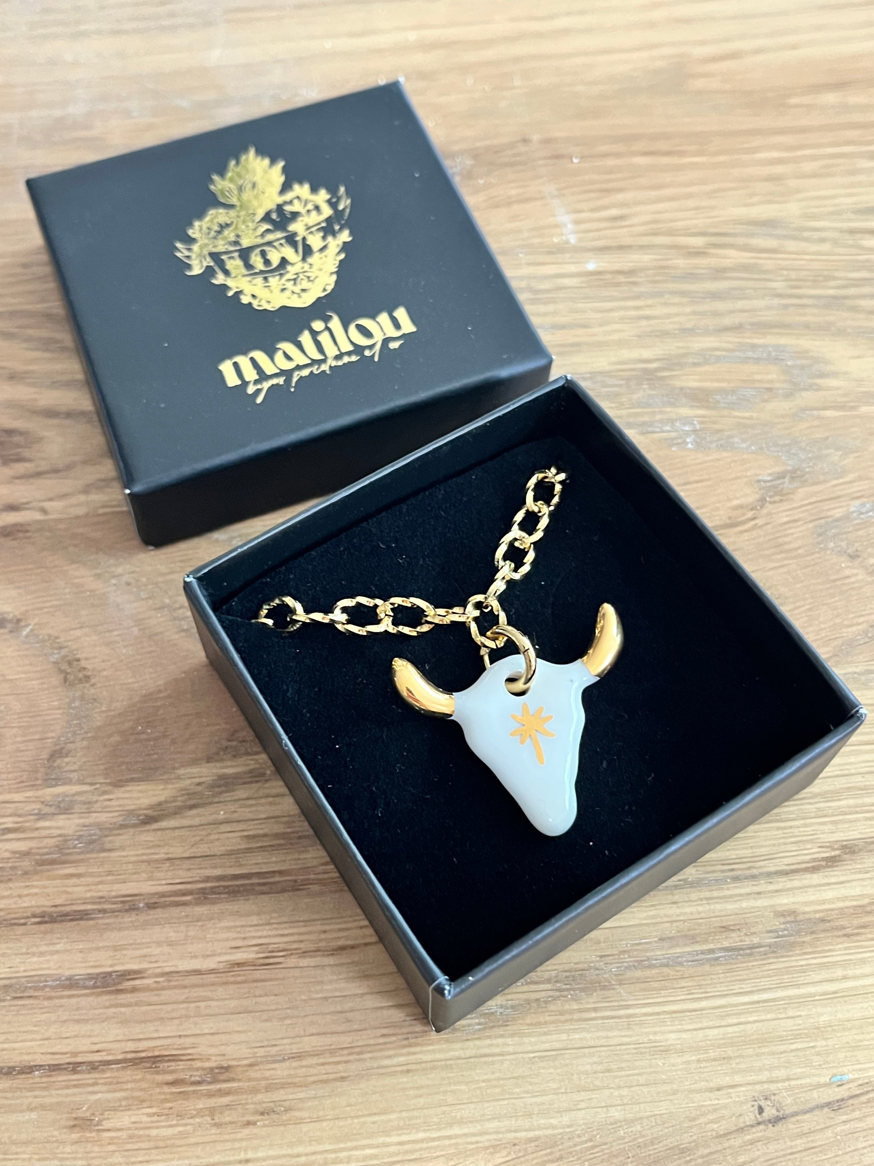 collier à pendentif taureau en porcelaine blanche avec ses finitions brillantes à l'or fin sur les cornes et son motif d'étoile  dorée peintes à la main. 