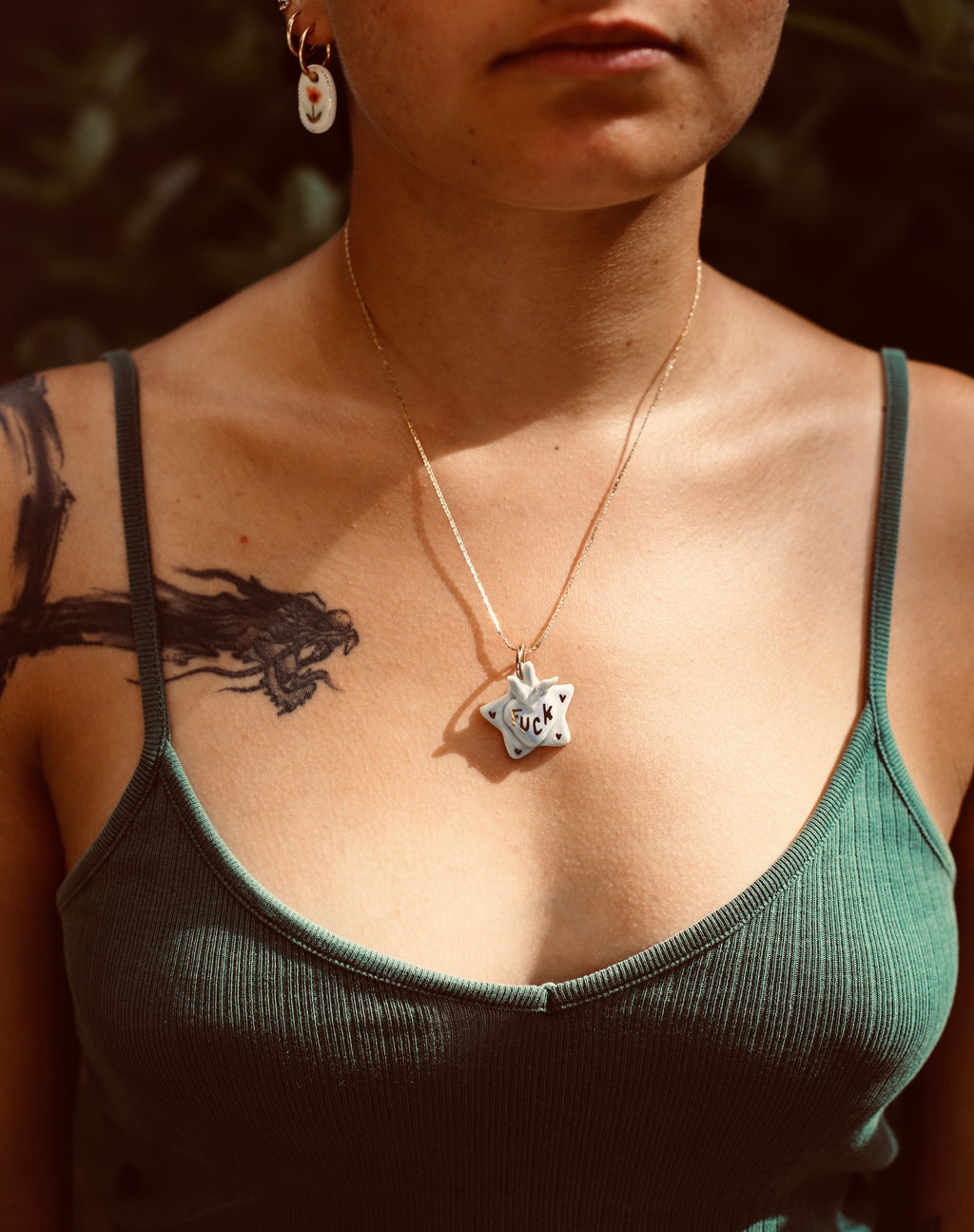 collier en acier inoxydable avec un pendentif en forme d'étoile en porcelaine couleur bleu ciel avec un coeur ex-voto et une inscription fuck écrite à l'or liquide avec des détails à l'or 