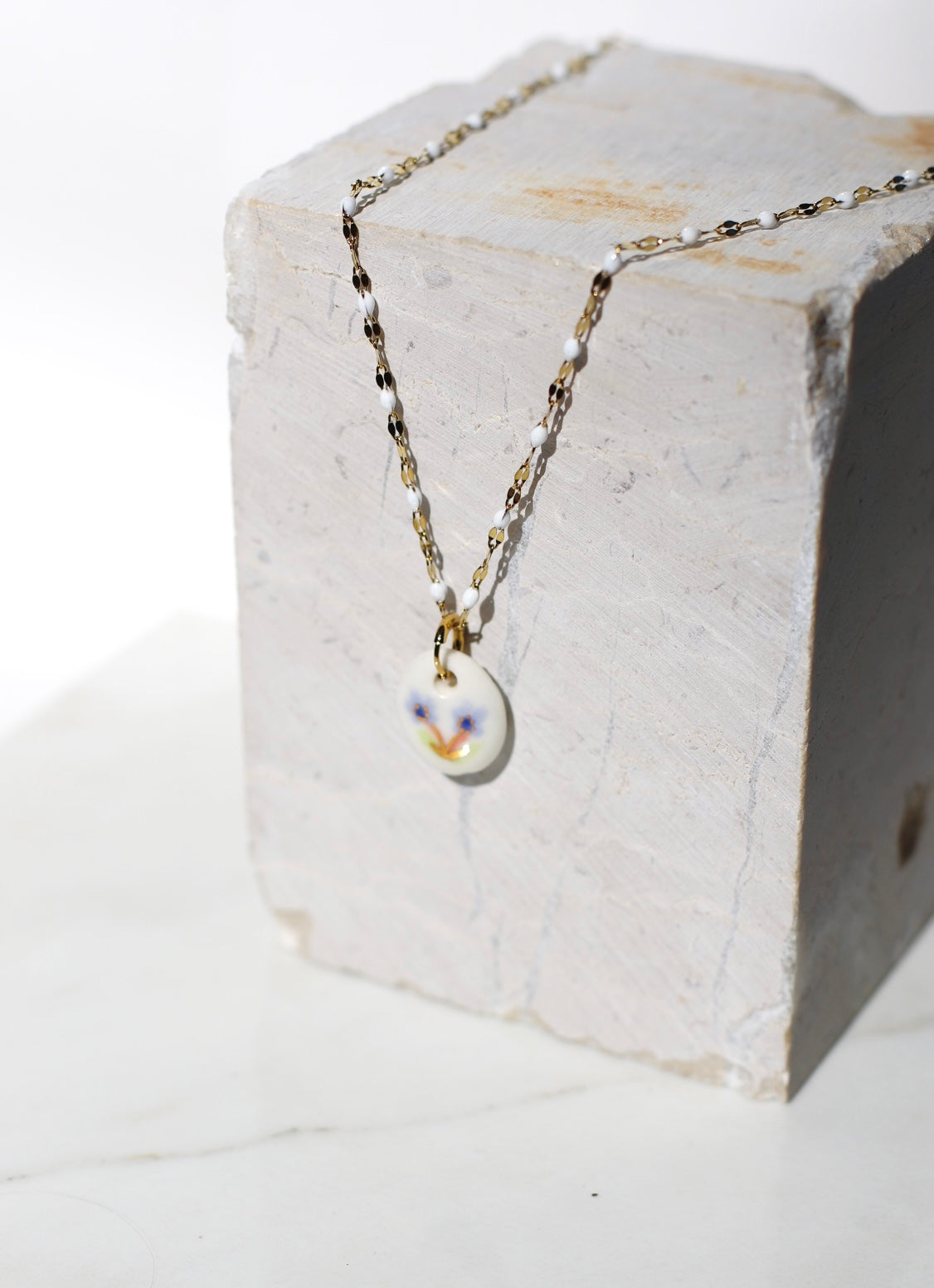 pendentif de collier fabriqué en porcelaine avec un motif floral peint à la main 