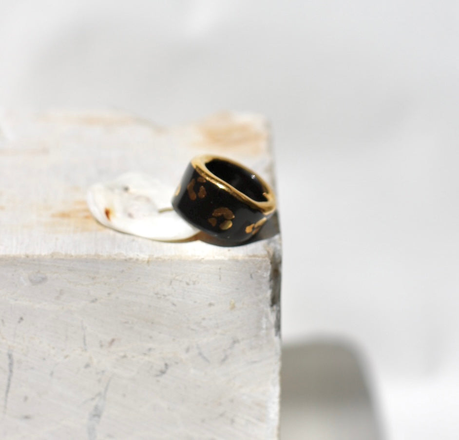 Une bague en porcelaine noir émaillée en taille 49, à motif léopards avec des tâches d'or liquide