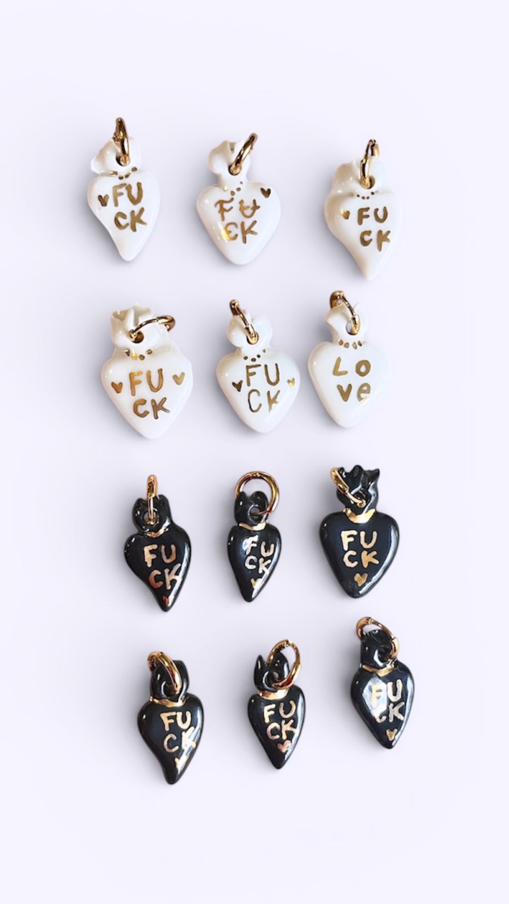 petit collier pendentif en porcelaine noire brillante, sculpté en forme de cœur avec le message d'or FUCK peint à la main.