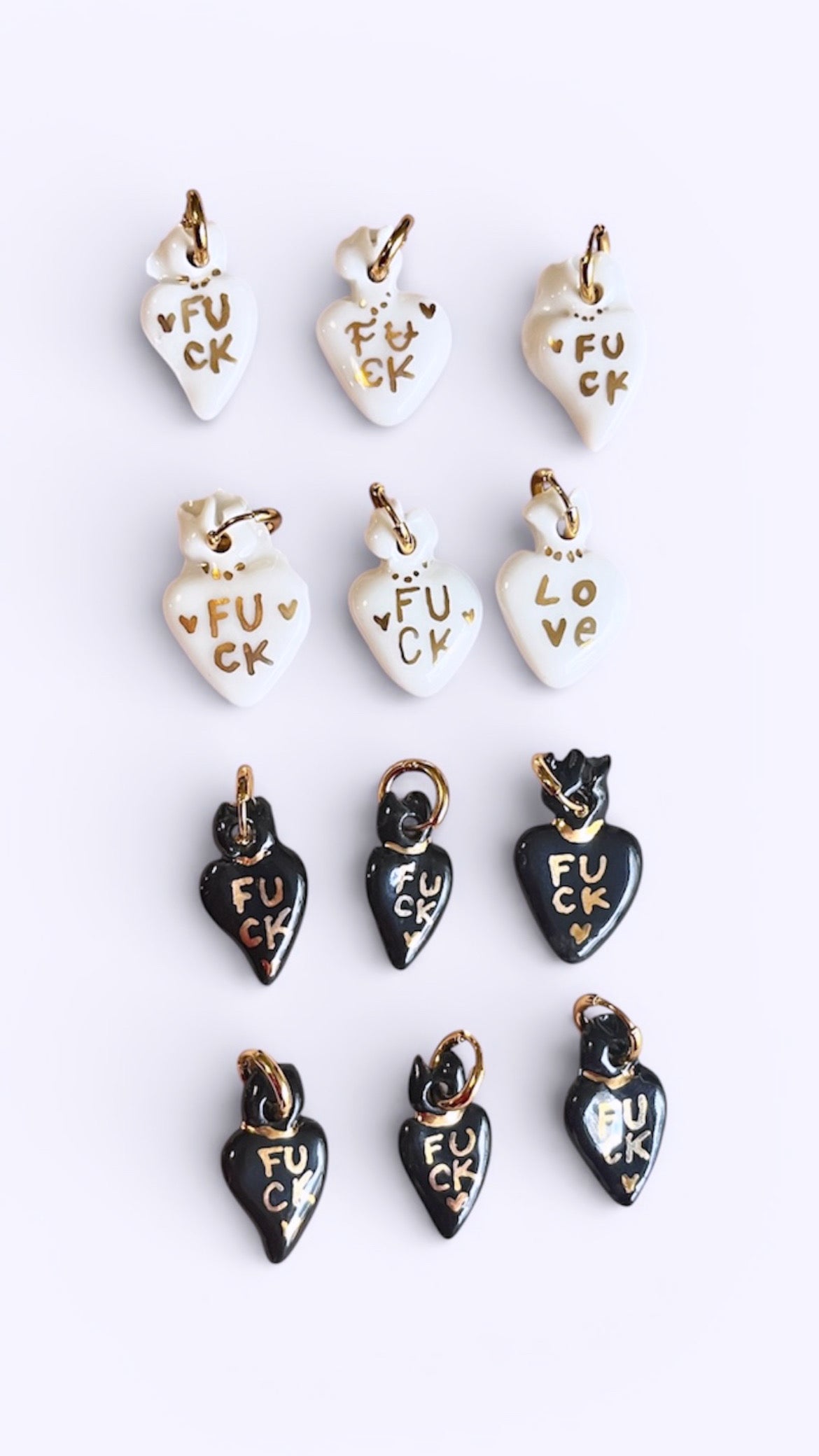 petit collier pendentif en porcelaine noire brillante, sculpté en forme de cœur avec le message d'or FUCK peint à la main.
